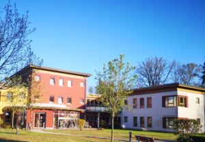 Mehrstöckiges Gebäude mit Bäumen und Rasenfläche