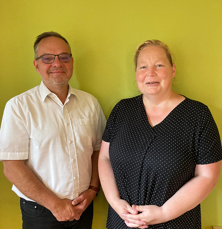 Zwei Personen stehen vor einer grünen Wand