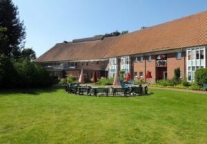 Eine Außenaufnahme eines großen Gebäudes mit rotem Dach und angrenzendem Garten.