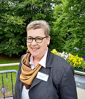 Person auf einem Balkon vor einer grünen Landschaft