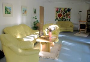 Gemütlicher Aufenthaltsraum mit gelben Sofas und Holztisch