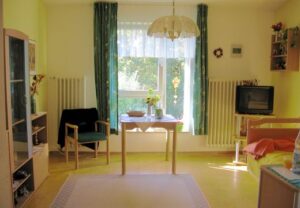 Ein gemütlich eingerichtetes Wohnzimmer mit einem großen Fenster und Tisch.