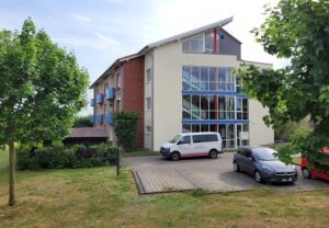 Mehrstöckiges Gebäude mit Glasfassade und Autos auf einem Parkplatz