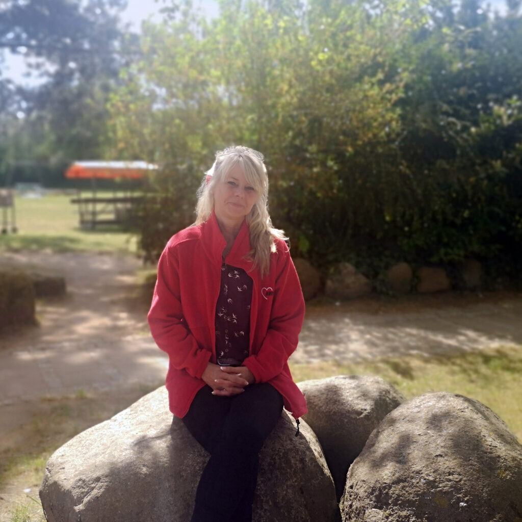 Eine Frau sitzt draußen auf einem großen Stein.