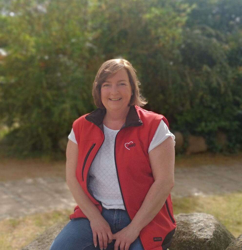 Frau in AWO-Weste draußen lächelnd