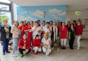 Gruppe von Menschen in Arbeitskleidung, die zusammen in einem Flur vor einem Wandbild posieren.
