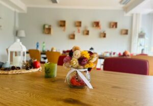 Ein dekorativer Raum mit einem Holztisch und bunten Zierpflanzen in einem Glasgefäß.