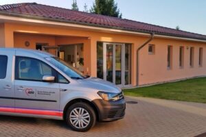 Ein AWO-Fahrzeug vor einem eingeschossigen Gebäude.