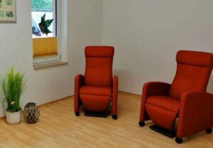 Zwei orangefarbene Sessel in einem schlicht eingerichteten Raum