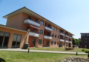 Mehrstöckiges Wohngebäude mit Balkonen und Rasenfläche im Vordergrund