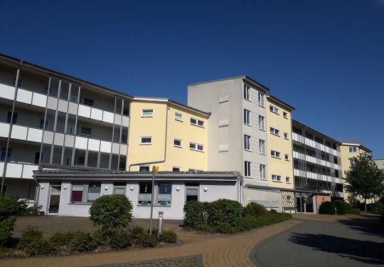 Mehrstöckiges Wohngebäude bei strahlend blauem Himmel.
