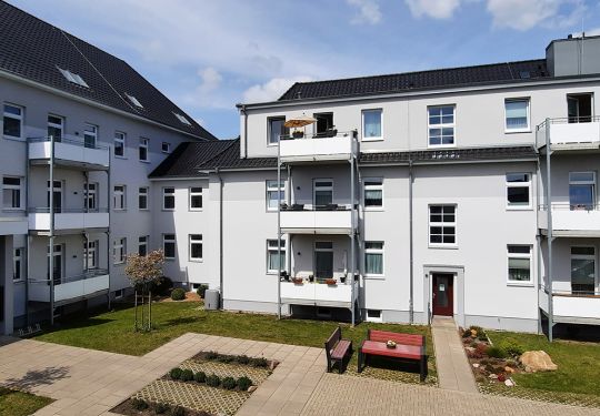 Ein moderner Gebäudekomplex mit mehreren Balkonen und einem gepflegten Innenhof.