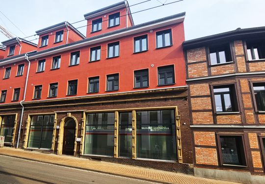 Mehrstöckiges rotes Gebäude mit Schaufenstern