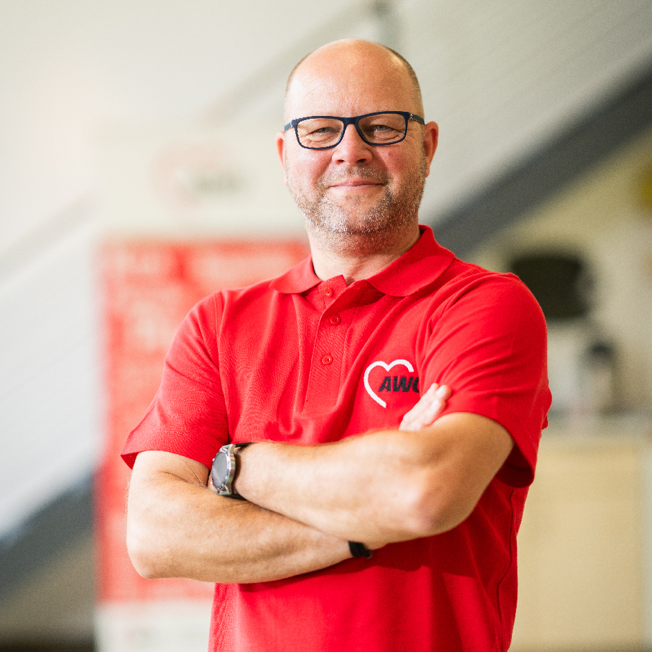 Mann in rotem AWO-Poloshirt vor unscharfem Hintergrund