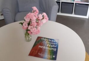 Ein runder Tisch mit einem Blumenstrauß und einem bunten Magazin.