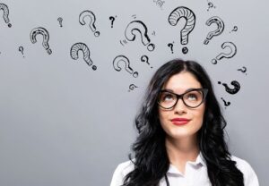 Frau vor grauem Hintergrund mit Fragezeichen