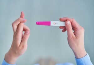 Hände halten einen positiven Schwangerschaftstest