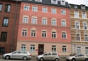 Ein mehrstöckiges Wohngebäude mit einer roten Fassade in einer Reihe von Stadthäusern