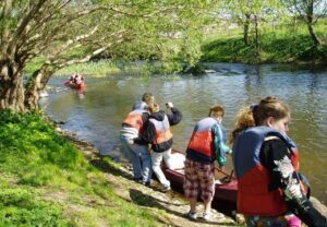 Gruppe von Menschen beim Kanufahren an einem Flussufer