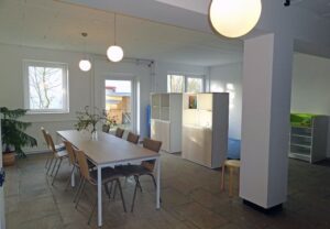 Innenansicht eines hellen Raumes mit Tischen und Stühlen