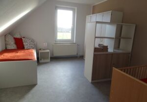 Innenansicht eines Zimmers mit Bett und Regal