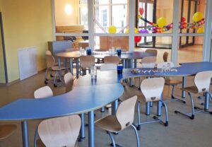 Innenansicht eines bunt dekorierten Raumes mit Tischen und Stühlen.