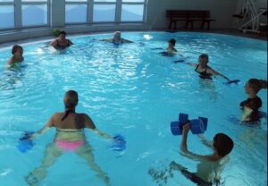 Mehrere Personen nehmen an einem Aquafitness-Kurs in einem Schwimmbecken teil
