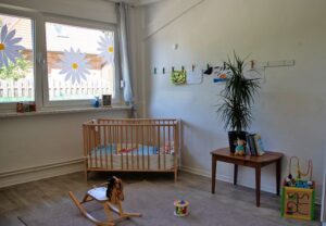Kinderzimmer mit Holzkinderbett, Schaukelpferd und Spielzeug