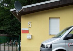 Außenansicht eines gelben Gebäudes mit der Nummer 5 und einem AWO-Fahrzeug