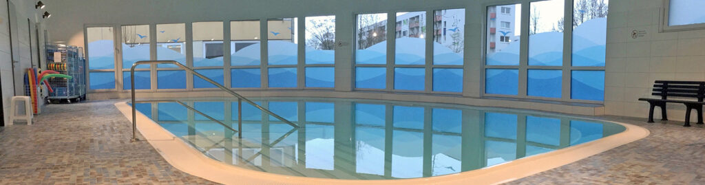 Ein Innenpool mit blauen Fenstern und Mosaikfliesenboden.