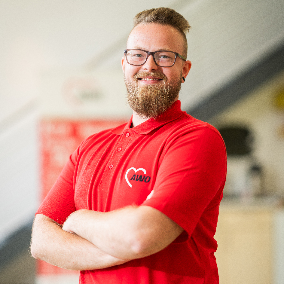 Mensch in rotem AWO-Poloshirt mit verschränkten Armen