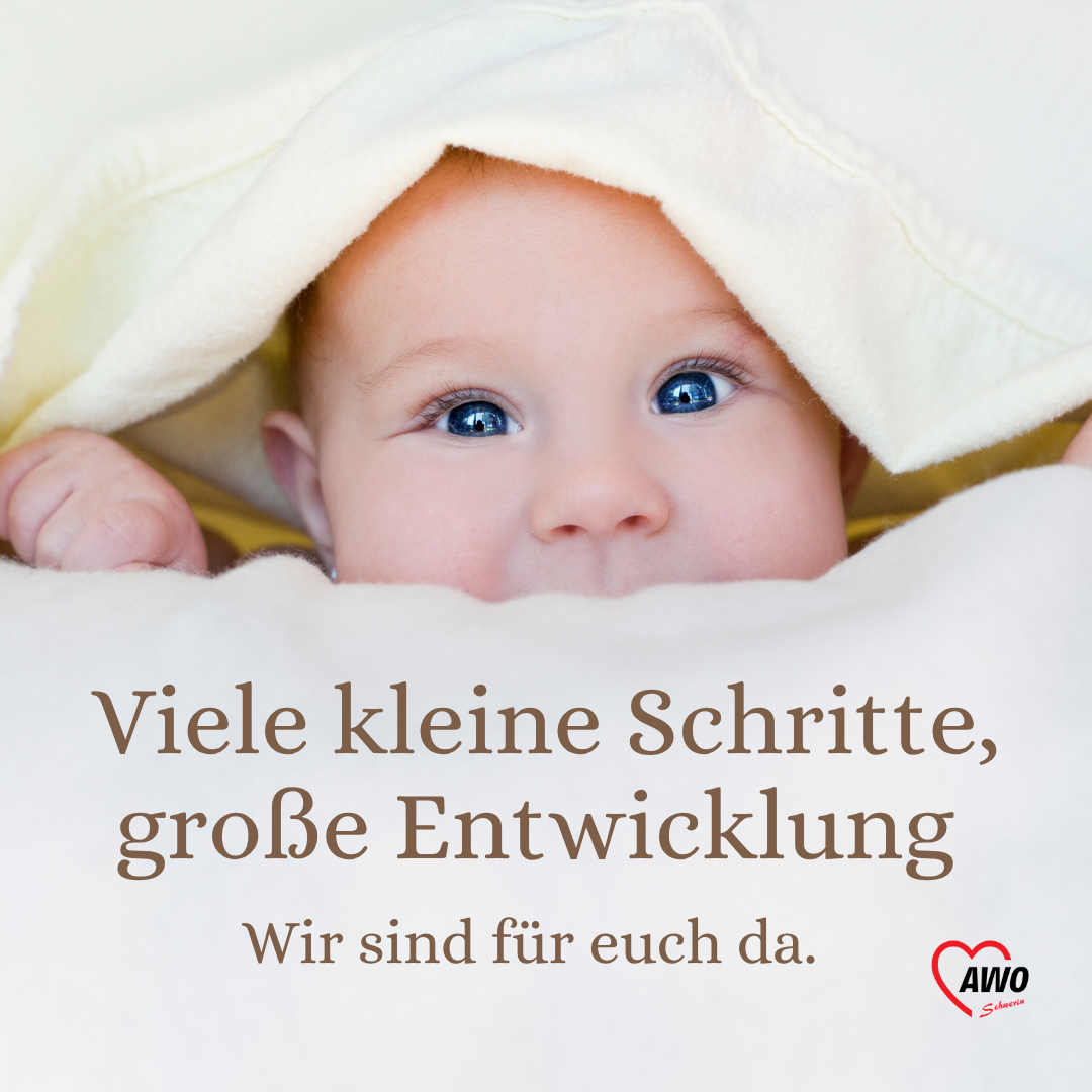 Ein Baby schaut unter einer Decke hervor.