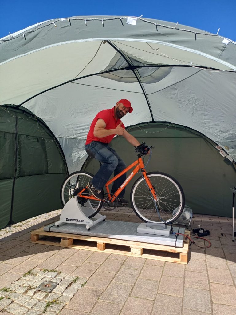 Person auf einem station&auml;ren Fahrrad in einem Zelt