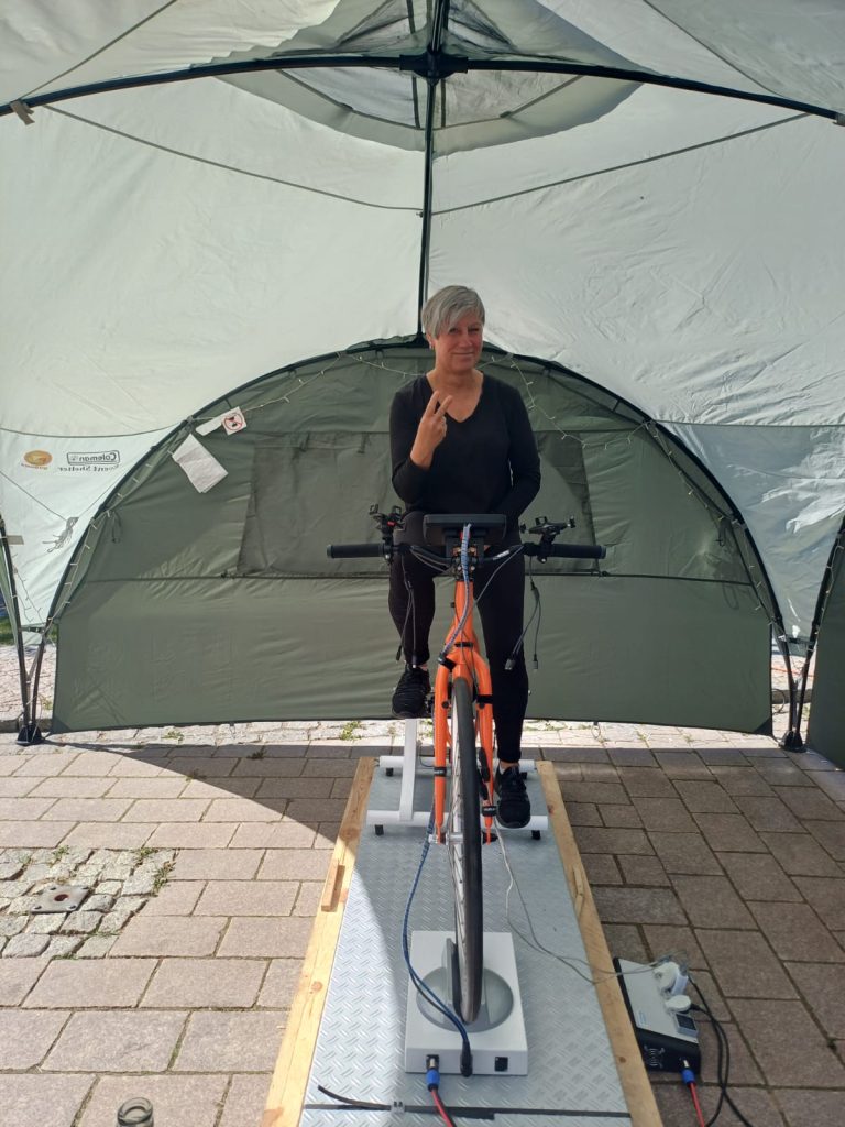 Person auf einem Fahrradtrainer unter einem Zelt.