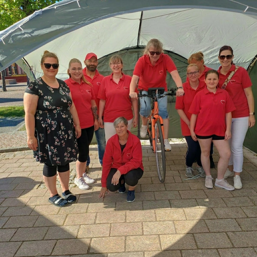 Gruppe von Menschen posiert unter einem Zelt mit einem Fahrrad