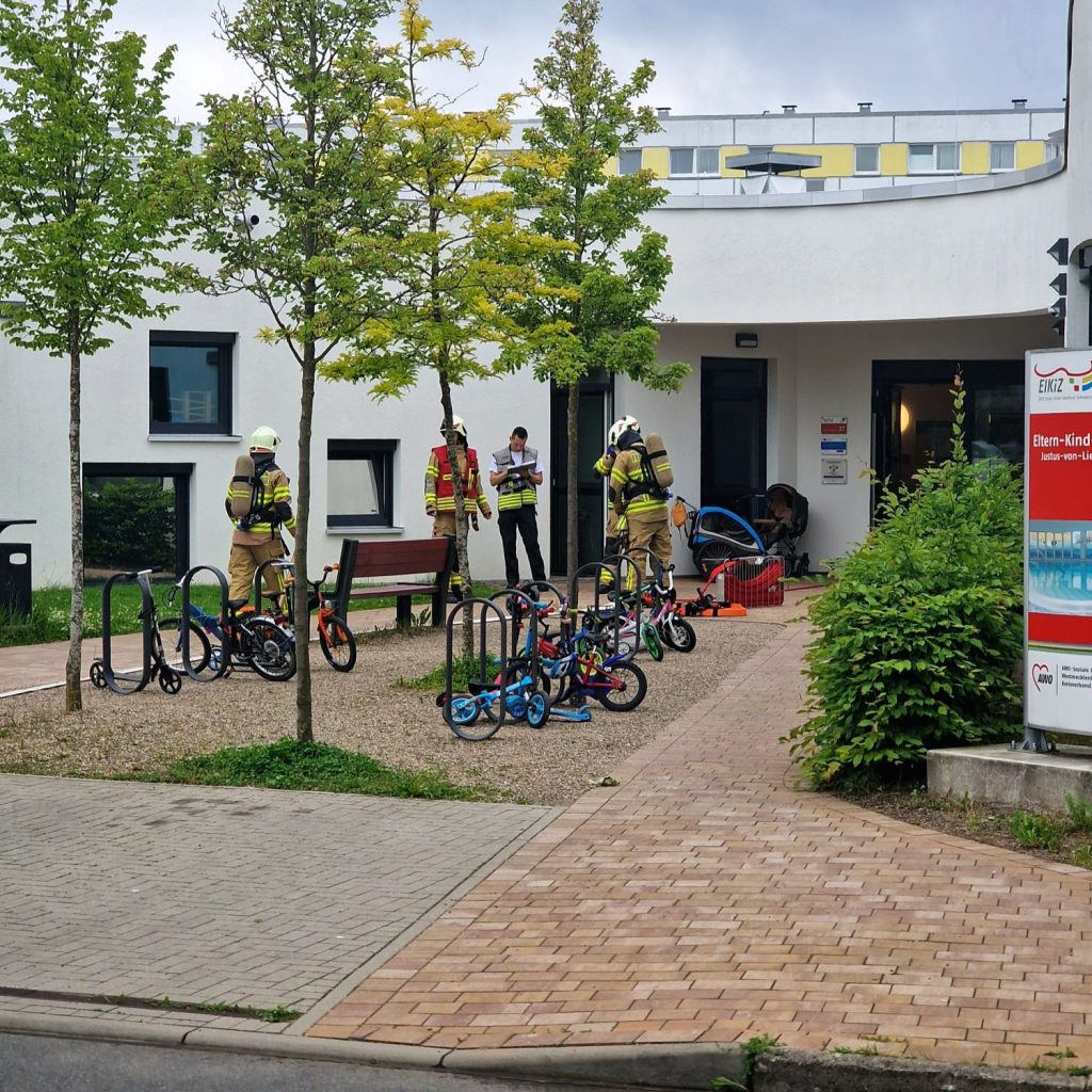Feuerwehrleute neben Fahrr&auml;dern vor einem Geb&auml;ude