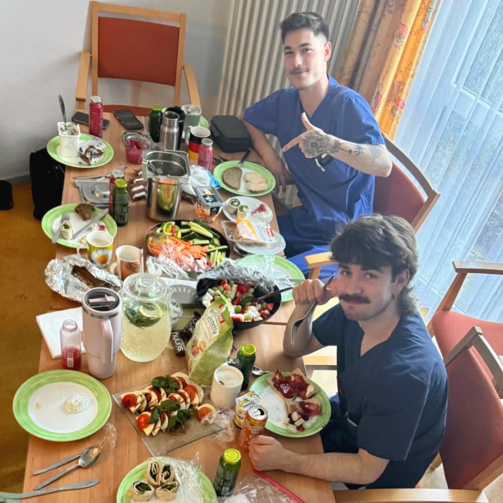 Zwei junge Männer, die an einem reich gedeckten Tisch sitzen.