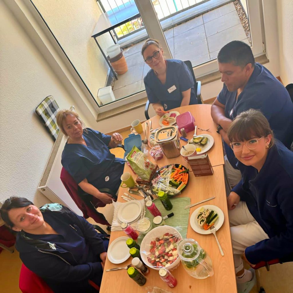 Fünf Personen, die an einem Tisch sitzen und ein gemeinsames Essen genießen.