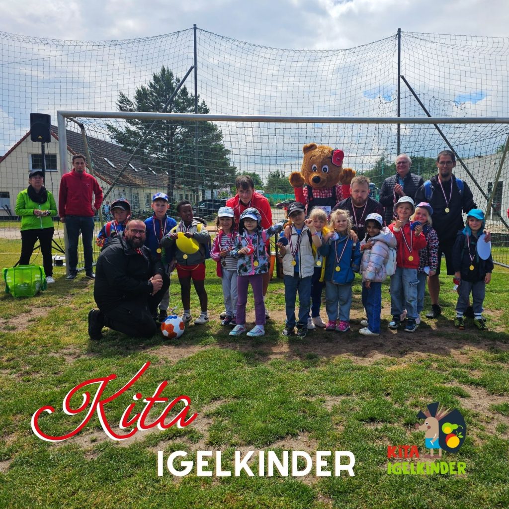 Kinder mit Medaillen und Betreuer vor einem Fu&szlig;balltor