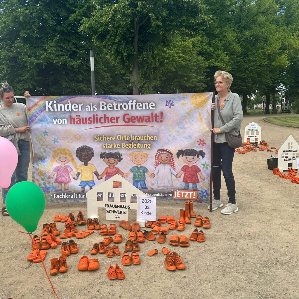 Demonstration gegen h&auml;usliche Gewalt mit Plakat und orangefarbenen Schuhen