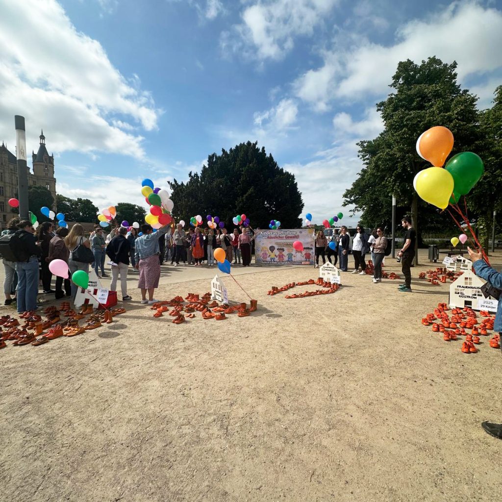 Menschenmenge mit Luftballons vor einem Schloss