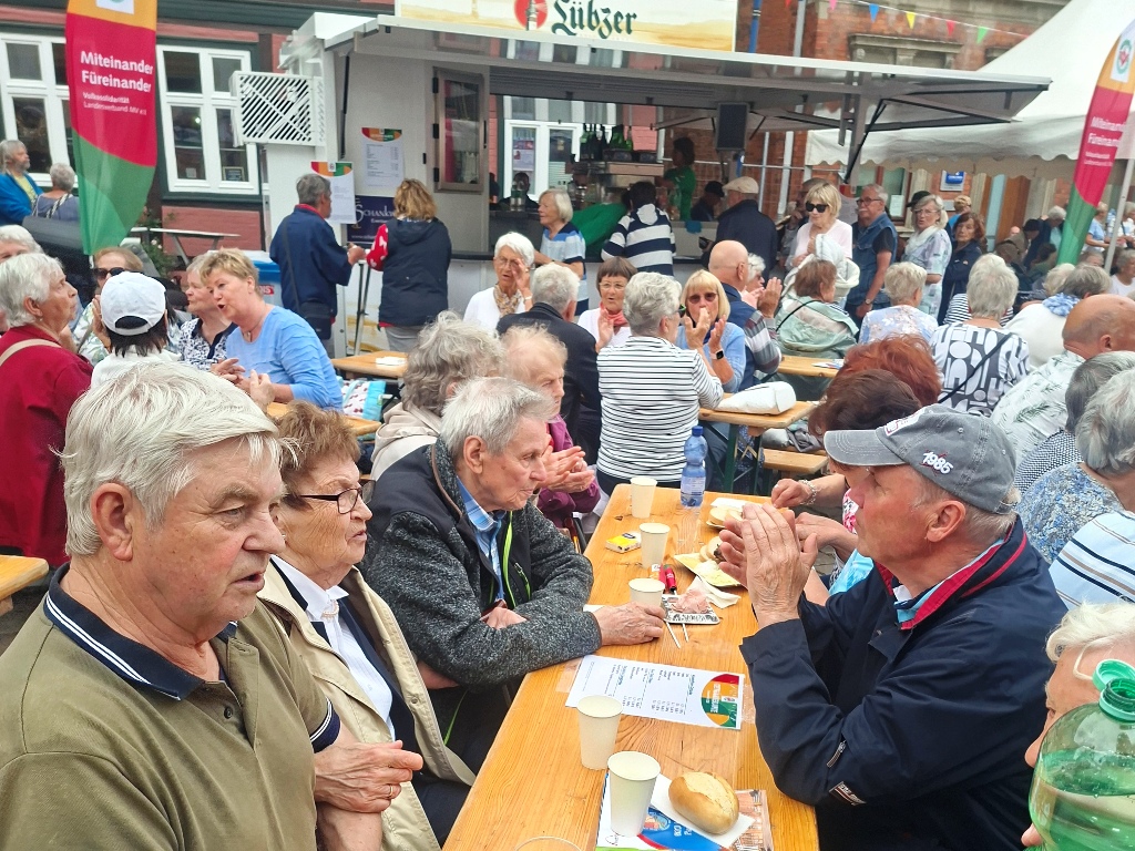 Gruppen von Menschen bei einem Fest an Bierzeltgarnituren sitzend