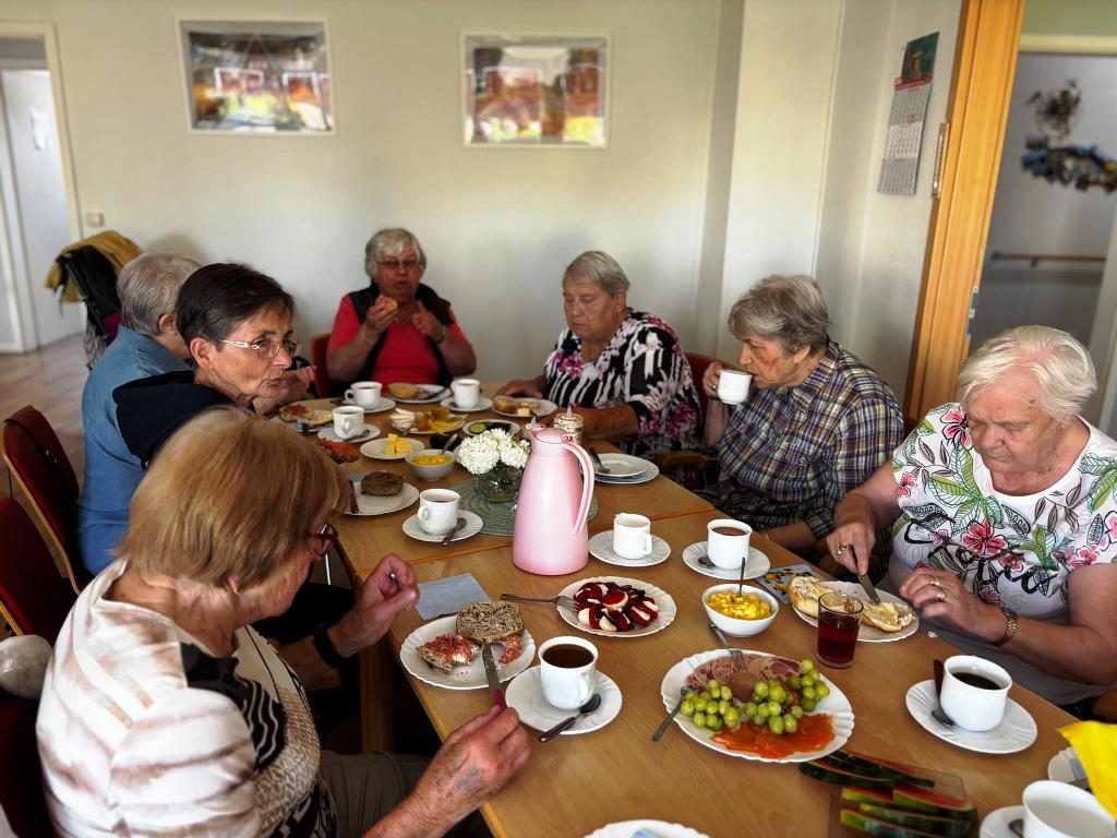 Menschen sitzen an einem gedeckten Tisch und essen.