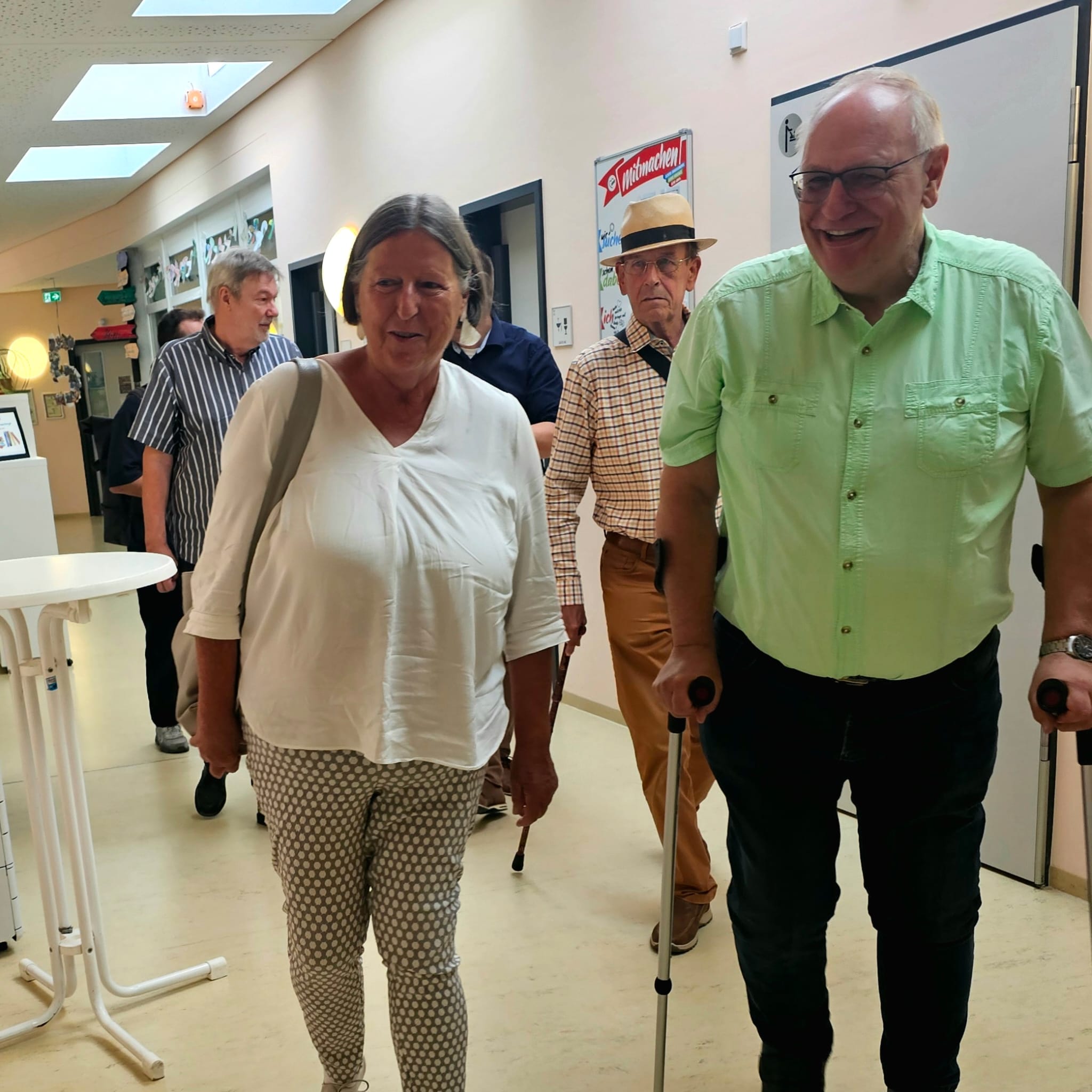 Mehrere Personen gehen fröhlich einen Korridor entlang