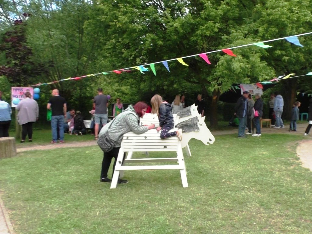 Menschen bei einem Outdoor-Event mit Holzpferden
