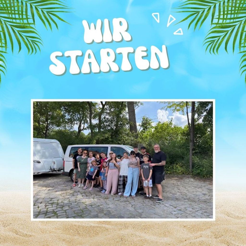 Eine Gruppe von Menschen steht vor einem weißen Van und Wohnwagen im Freien.