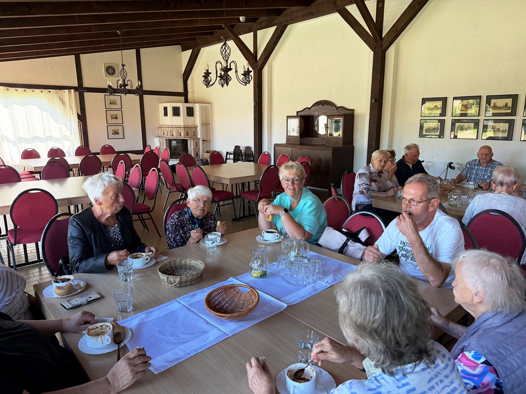 Gruppe älterer Menschen in einem Café, die gemeinsam an einem Tisch sitzen.