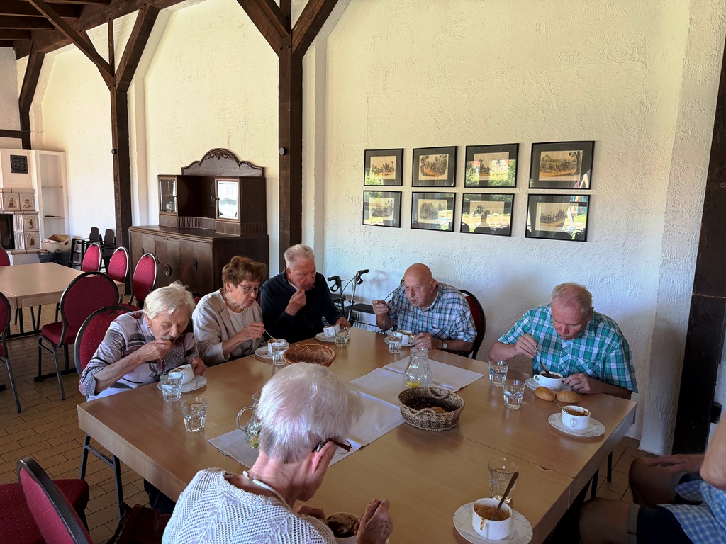 Gruppe älterer Menschen beim gemeinsamen Essen in einem Gemeinschaftsraum