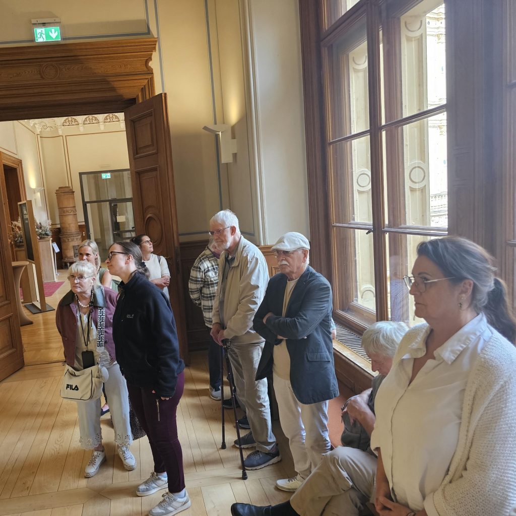 Eine Gruppe von Menschen in einem stilvollen Raum mit großen Fenstern.