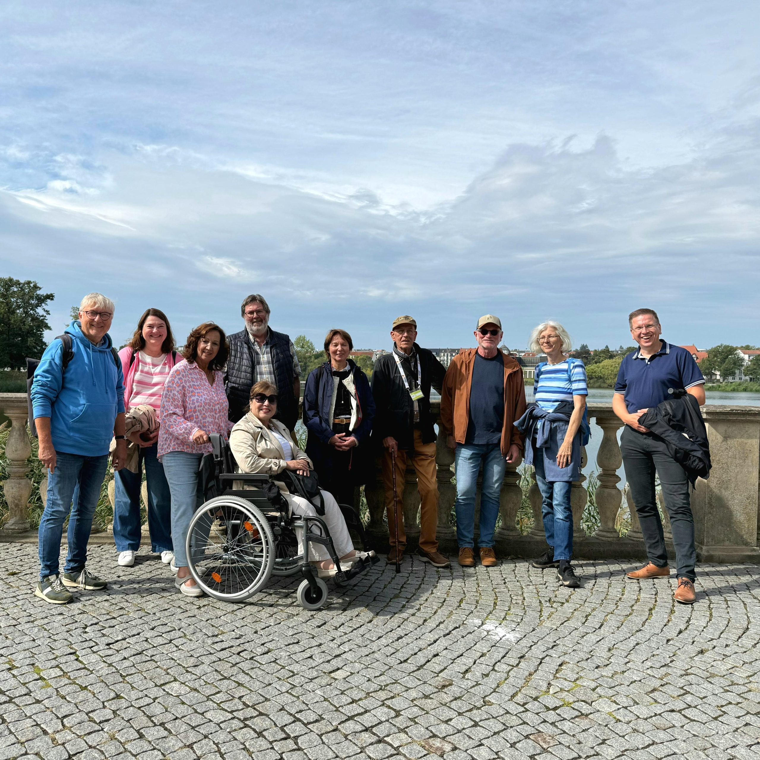 Gruppe von Menschen posiert für ein Foto im Freien vor einem Gewässer.